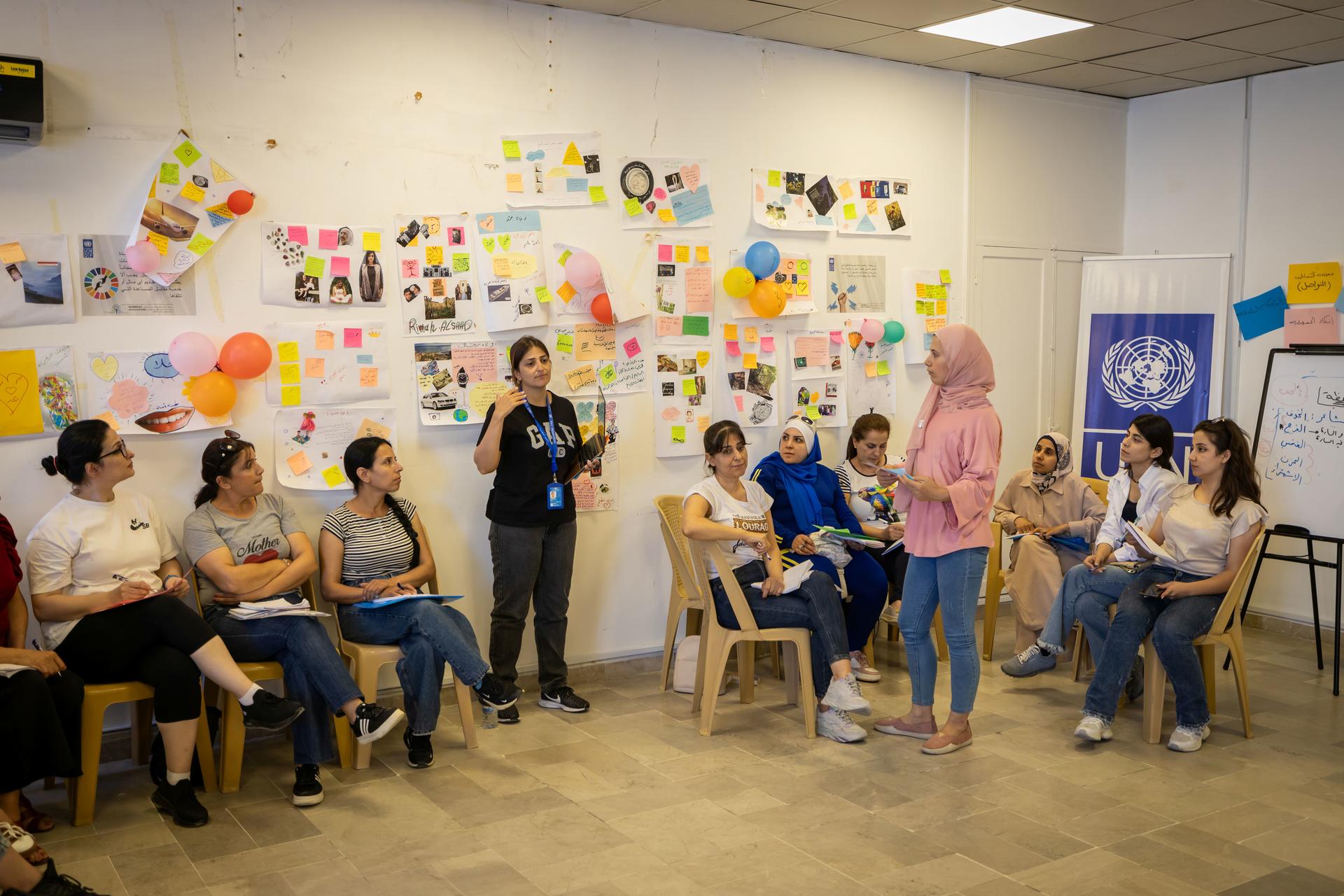 Group of people seated in a circle during a workshop; walls covered with colorful sticky notes.