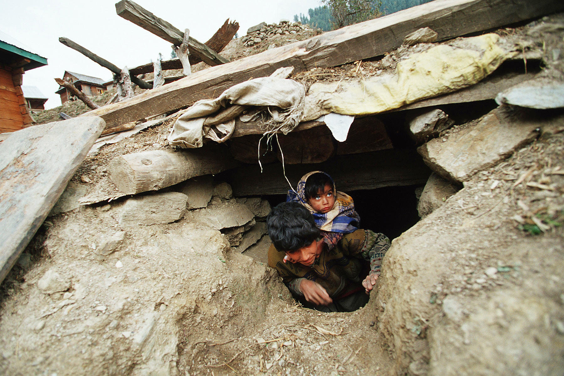 Person in dark clothing emerging from a hole in collapsed rubble and debris.