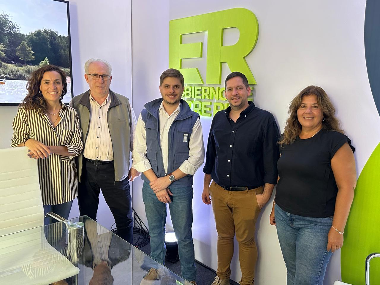 Group photo of six people in a bright showroom with a lime-green logo on the wall.
