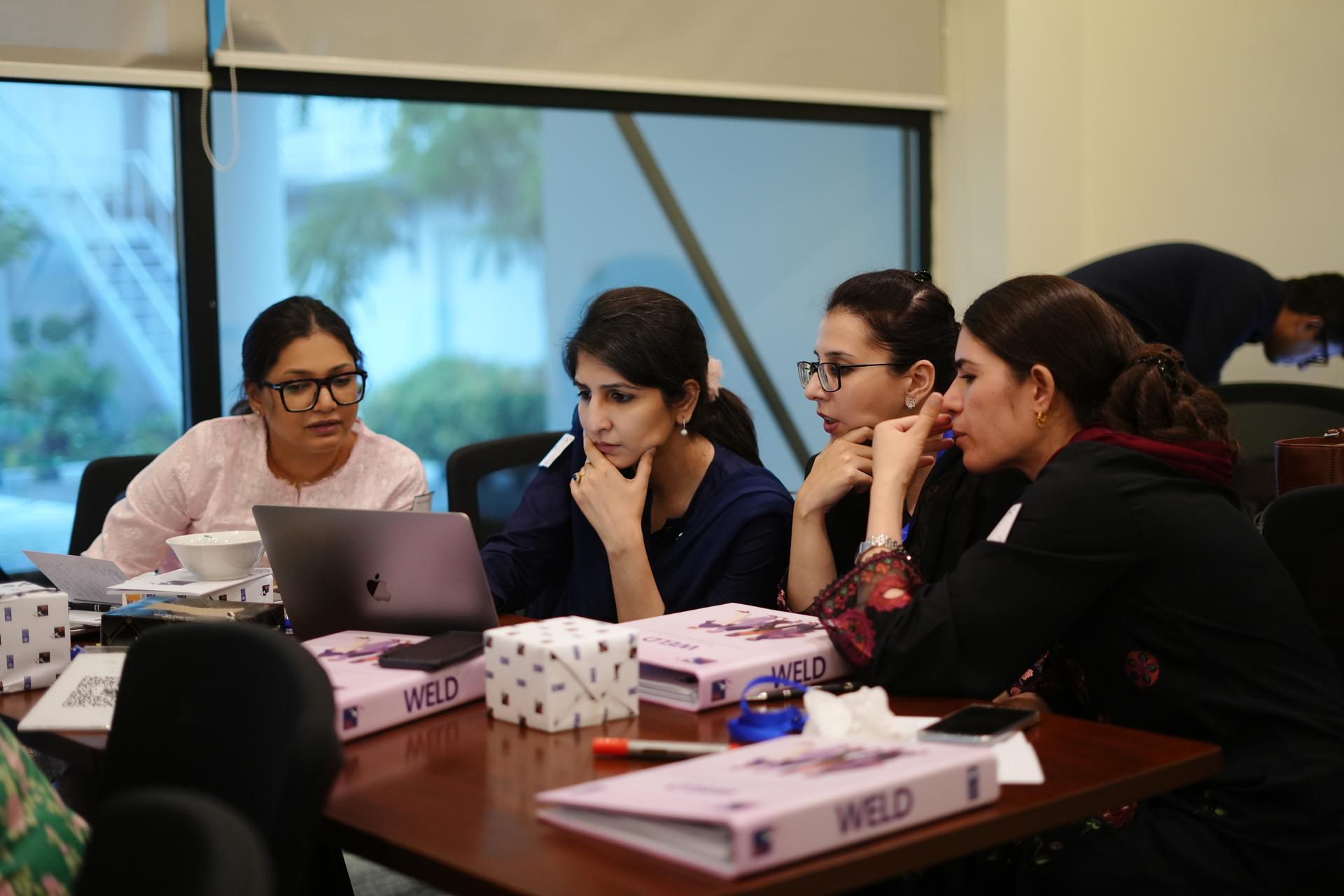 Photo: five people around a conference table with laptops and papers in a bright room.