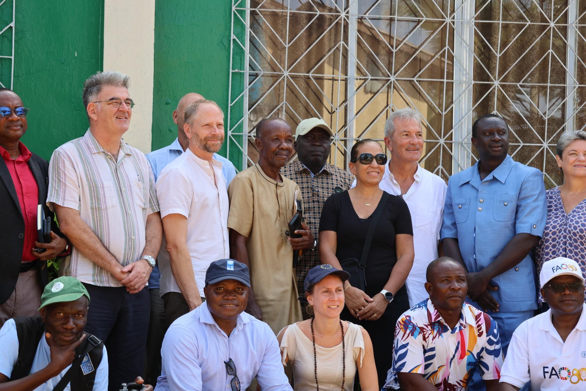 Group photo of a diverse group posing in front of a green building.