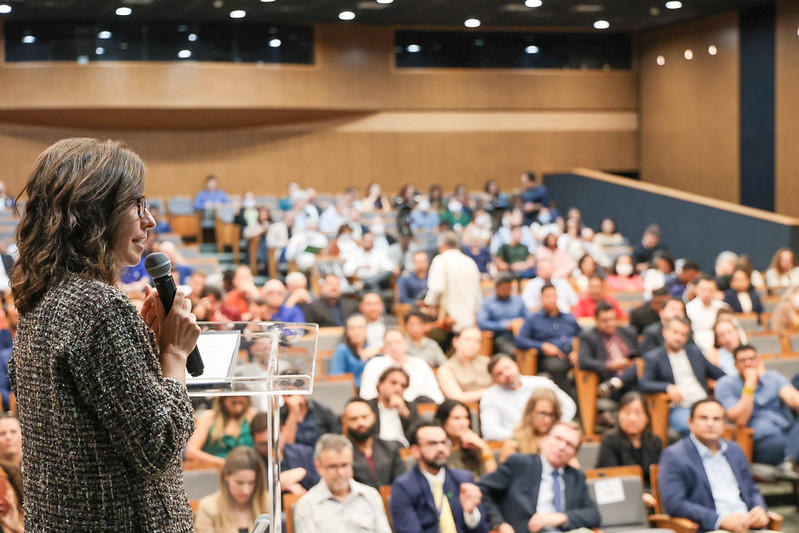 Photograph of a speaker addressing a large audience in a conference hall.