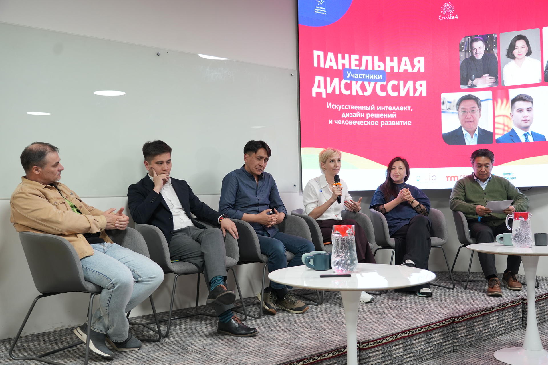Panel discussion with six people seated; modern room, large screen with Russian title behind.