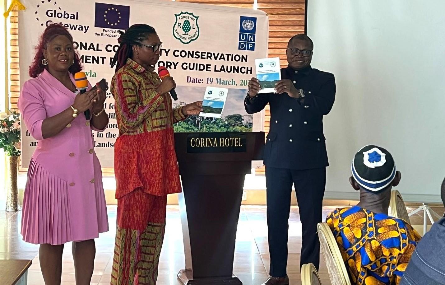 Four people on a stage at a conservation event, banner and podium in the background.