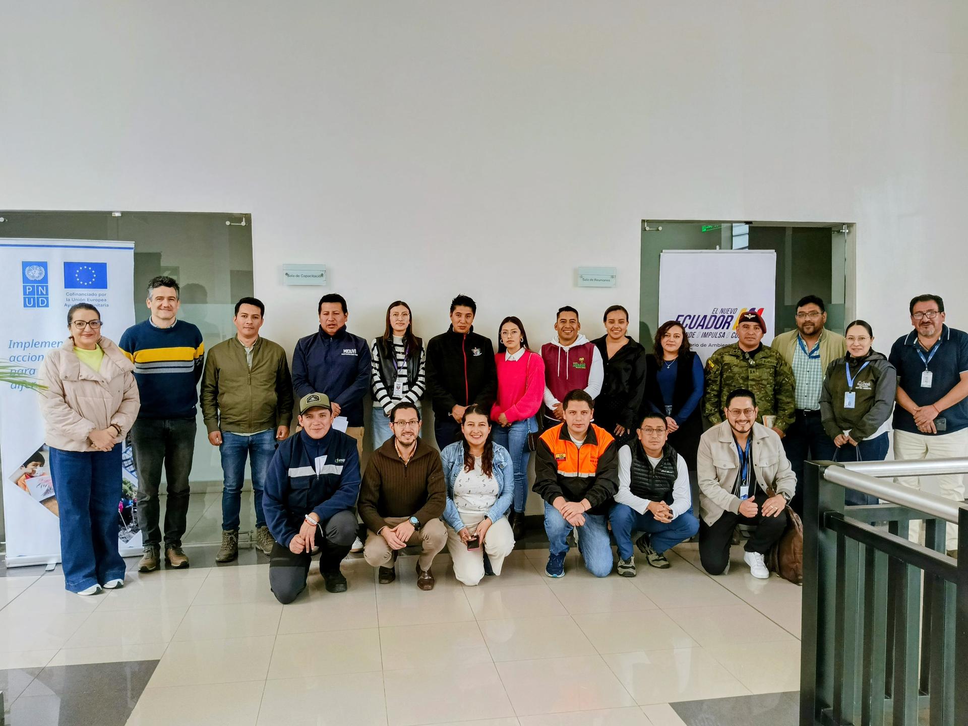 Group photo of people in a classroom, two rows posing beside a chalkboard.