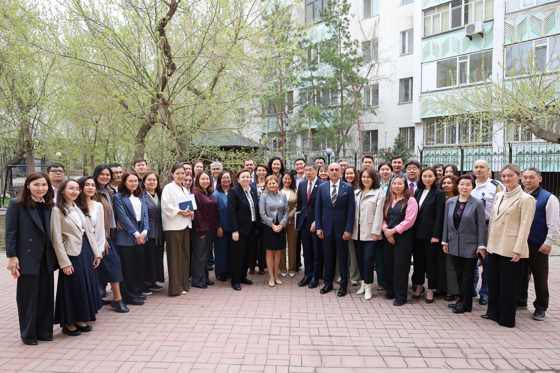 Group photo of a large group of professionals in business attire outdoors in a courtyard.