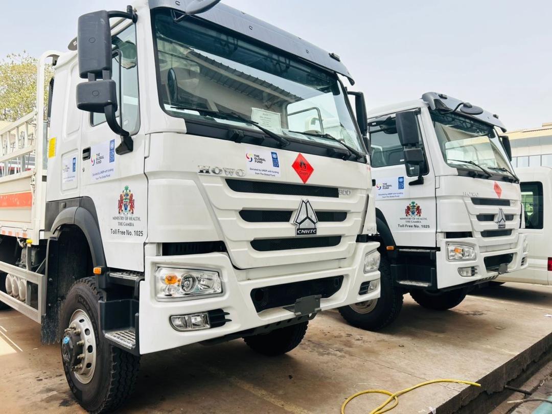 Front view of two white commercial trucks with company logos parked side by side.