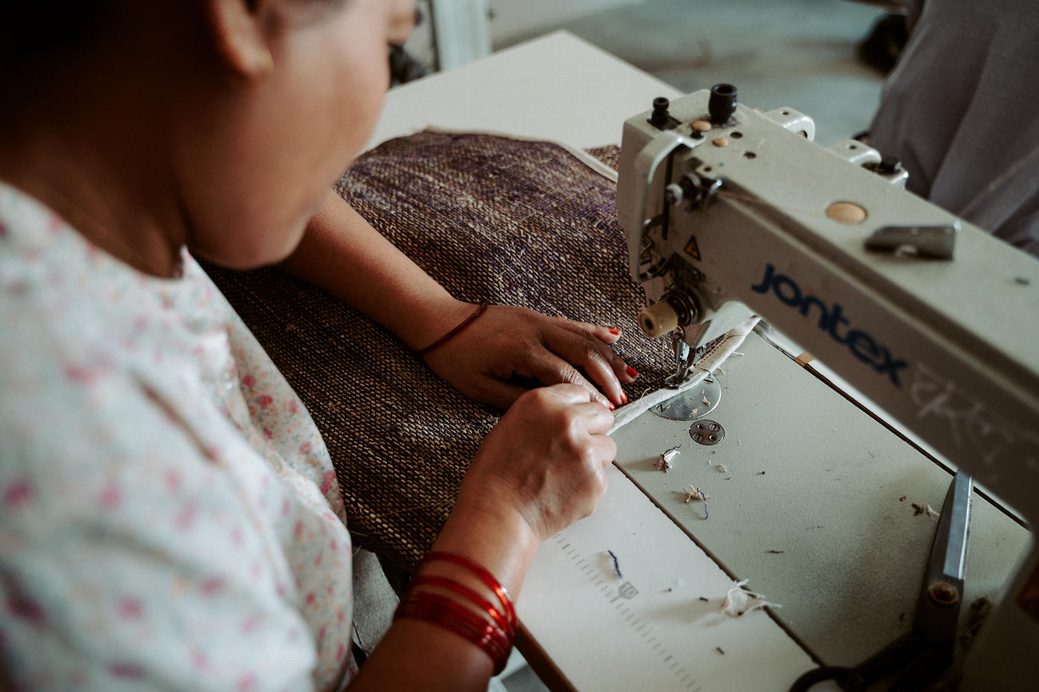 Close-up of hands guiding fabric through a Janome sewing machine.
