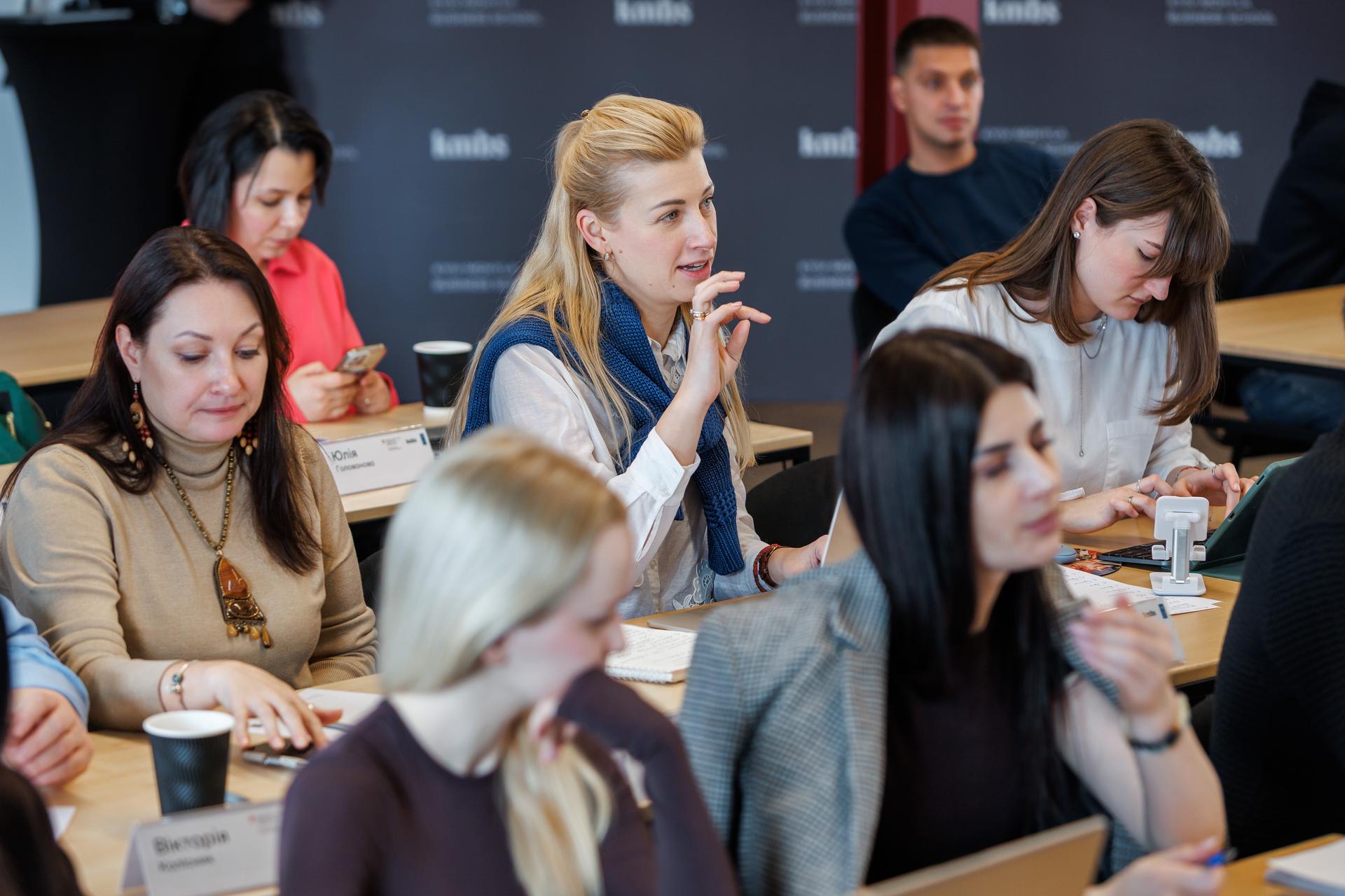 Photograph of students in a classroom lecture, some wearing masks, listening and taking notes.