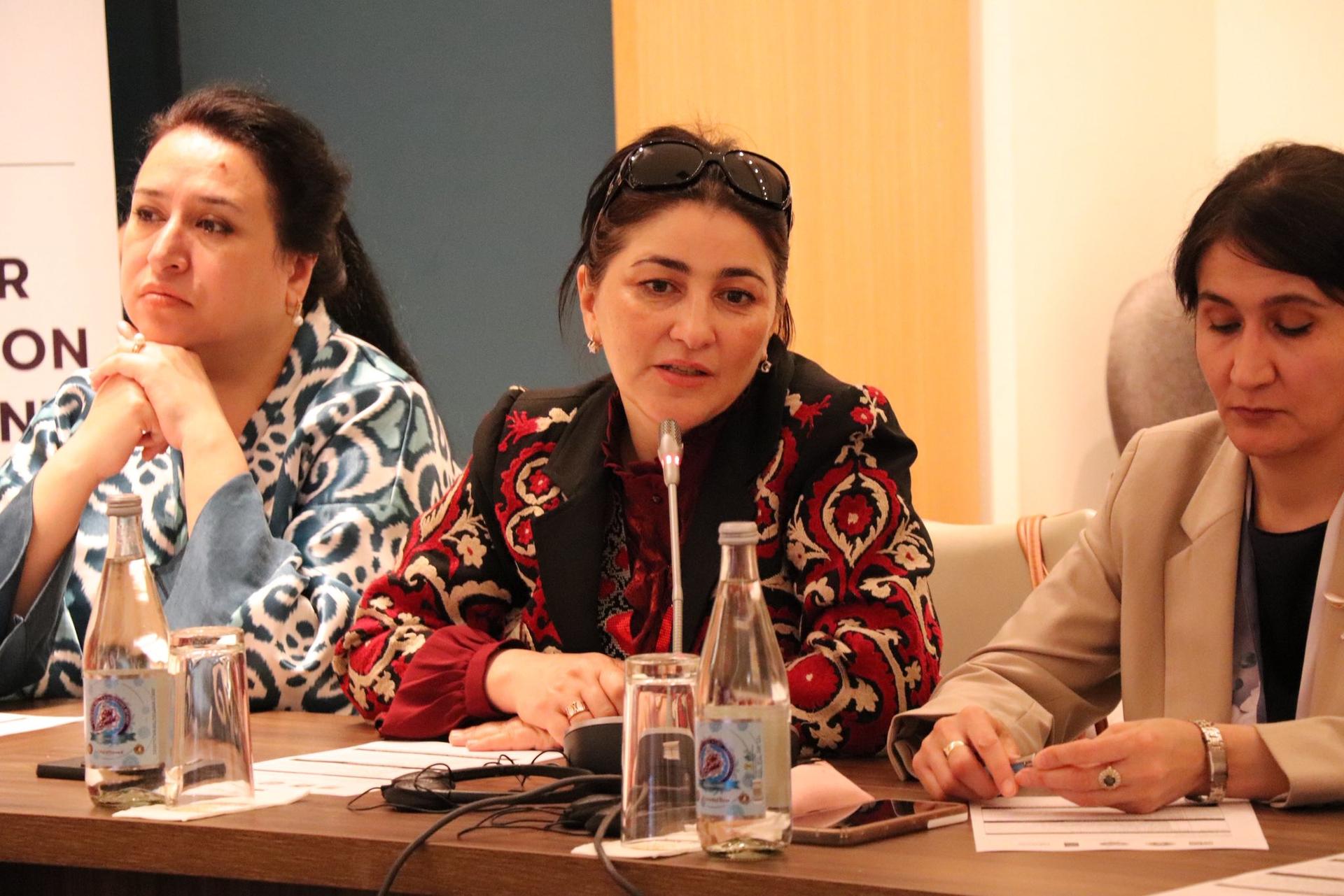 Photograph of a panel discussion with three people seated at a table and microphones.