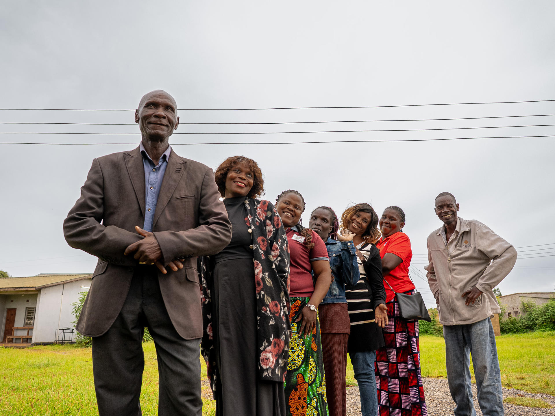 Photograph of a diverse group posing outdoors in front of a house.