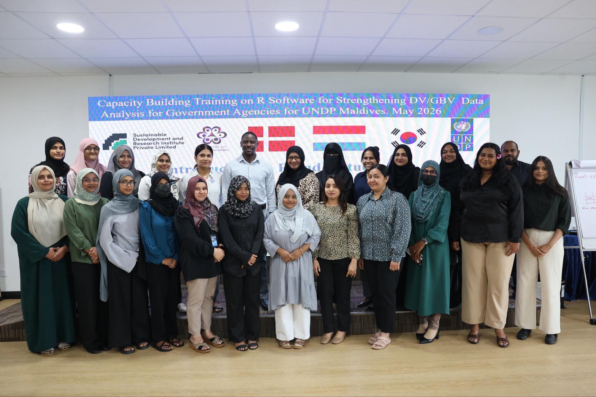 Diverse group of professionals posing on a stage in front of a conference banner with logos.