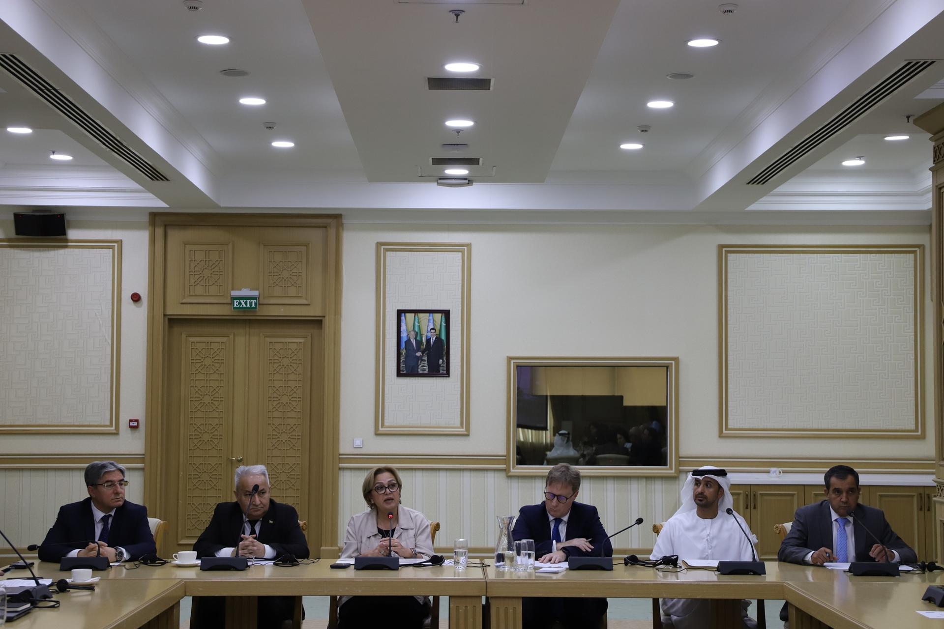 Group of professionals seated around a long conference table in a formal meeting room.