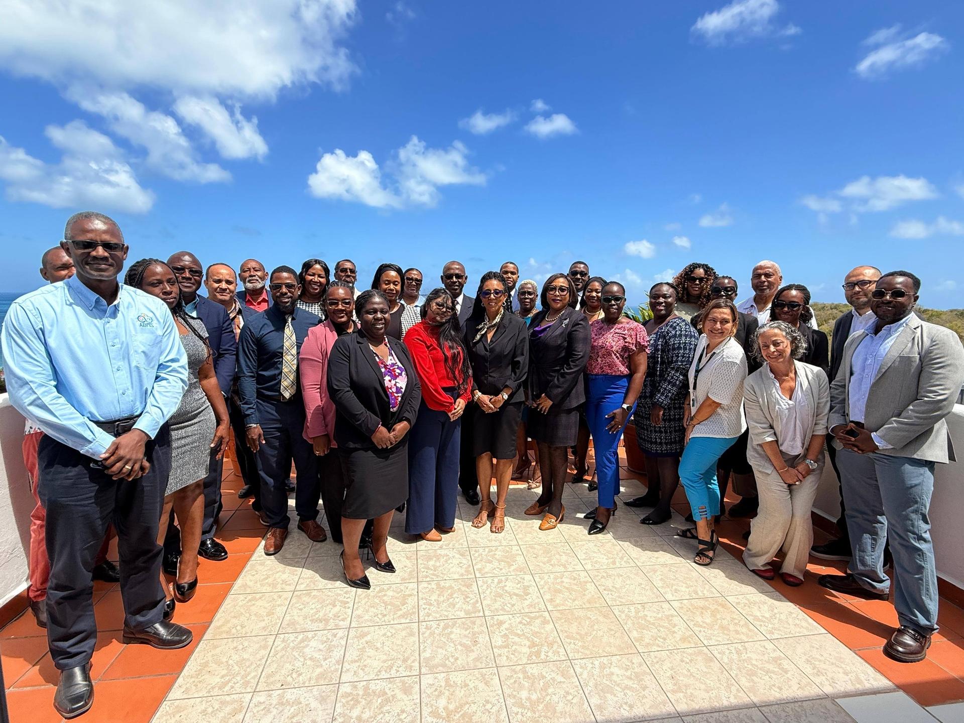Diverse group posing for a group photo on an orange-tiled rooftop under a blue sky.