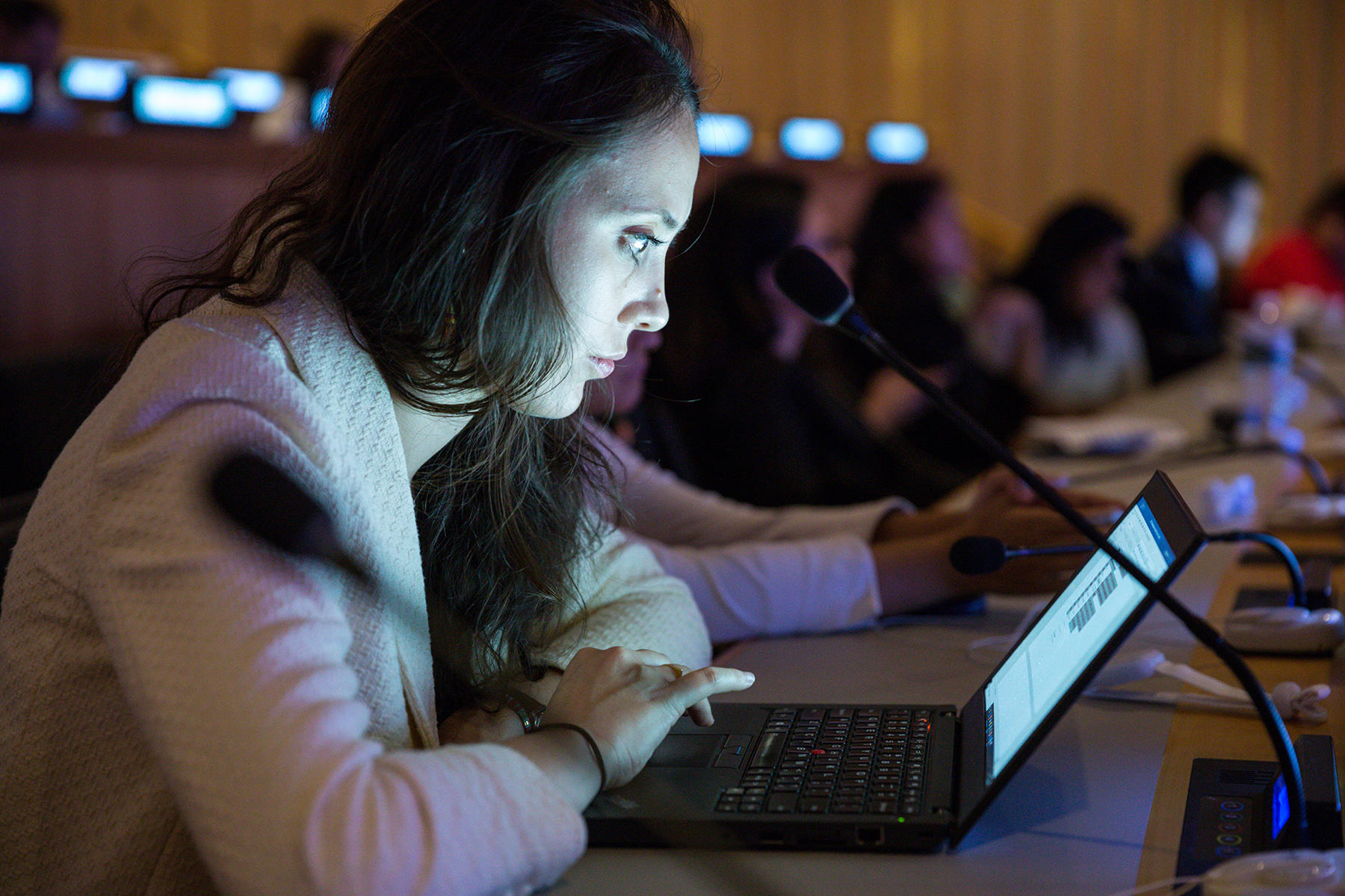 Woman with long hair using a laptop at a conference table.