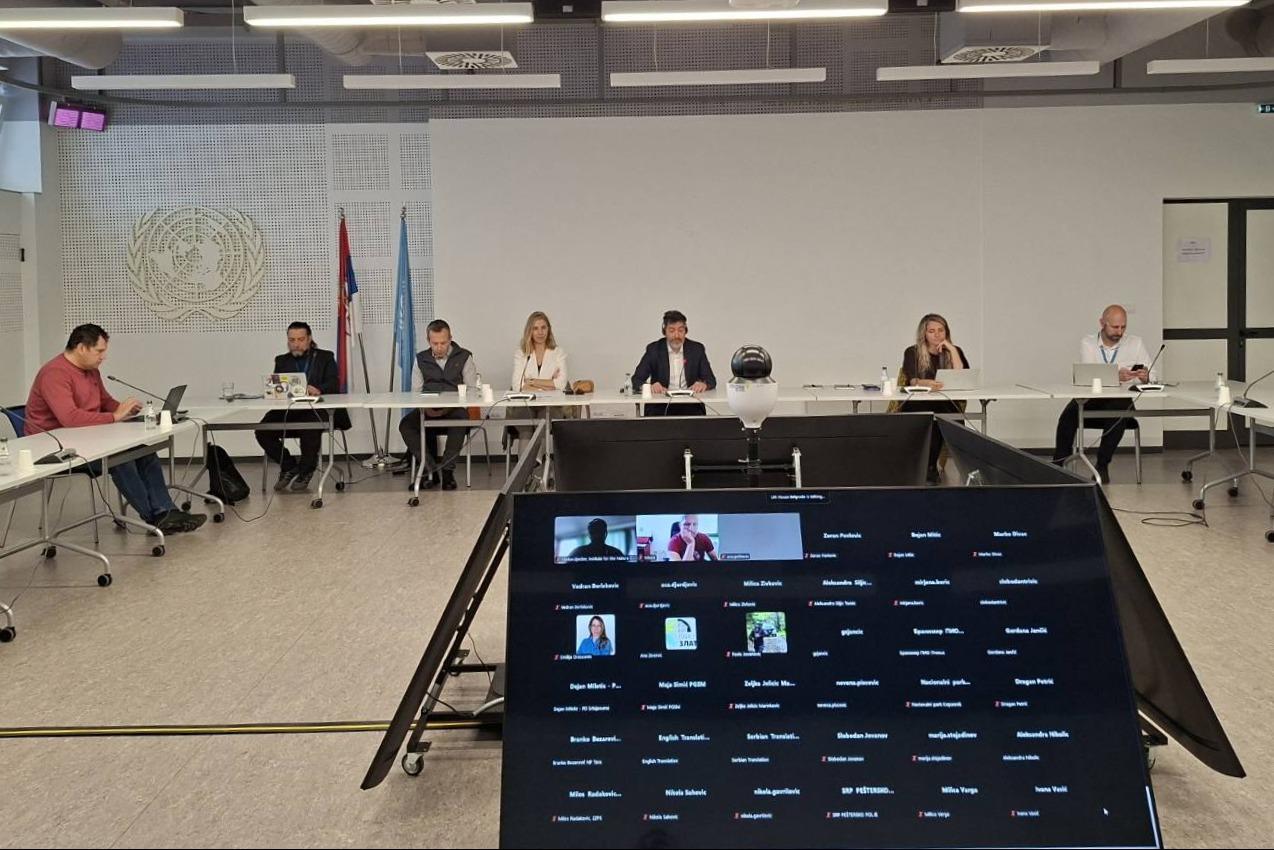 Photo: board members sit around a U-shaped conference table; video grid on screen.