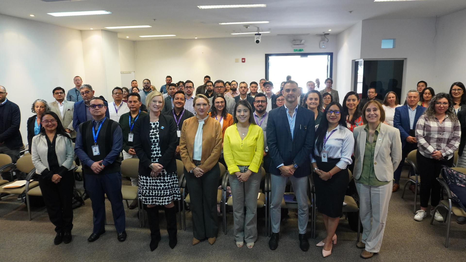 Large diverse group standing in a conference room for a group photo.