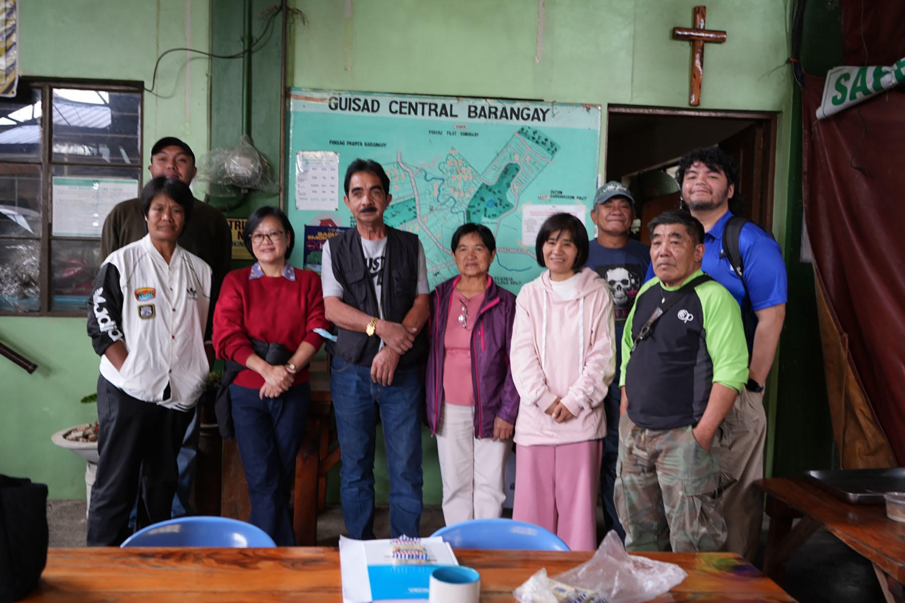 Group photo of people indoors with a cross on the wall and banners behind