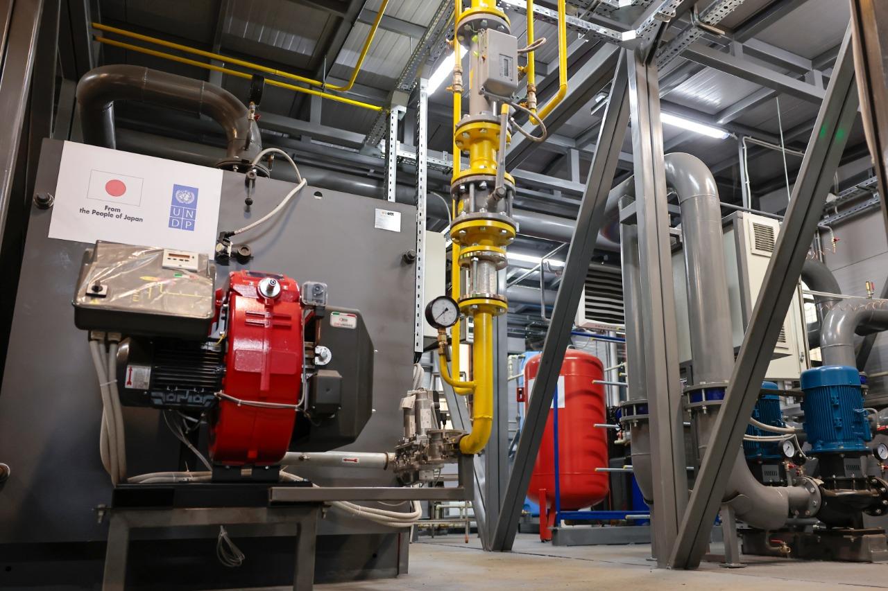 Industrial mechanical room with large pipes, valves, and red and blue pumps.