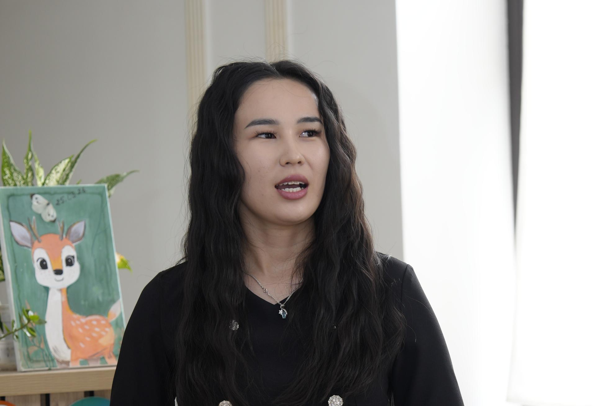 Person with long dark hair and blurred face stands in bright room; fox painting on easel visible.