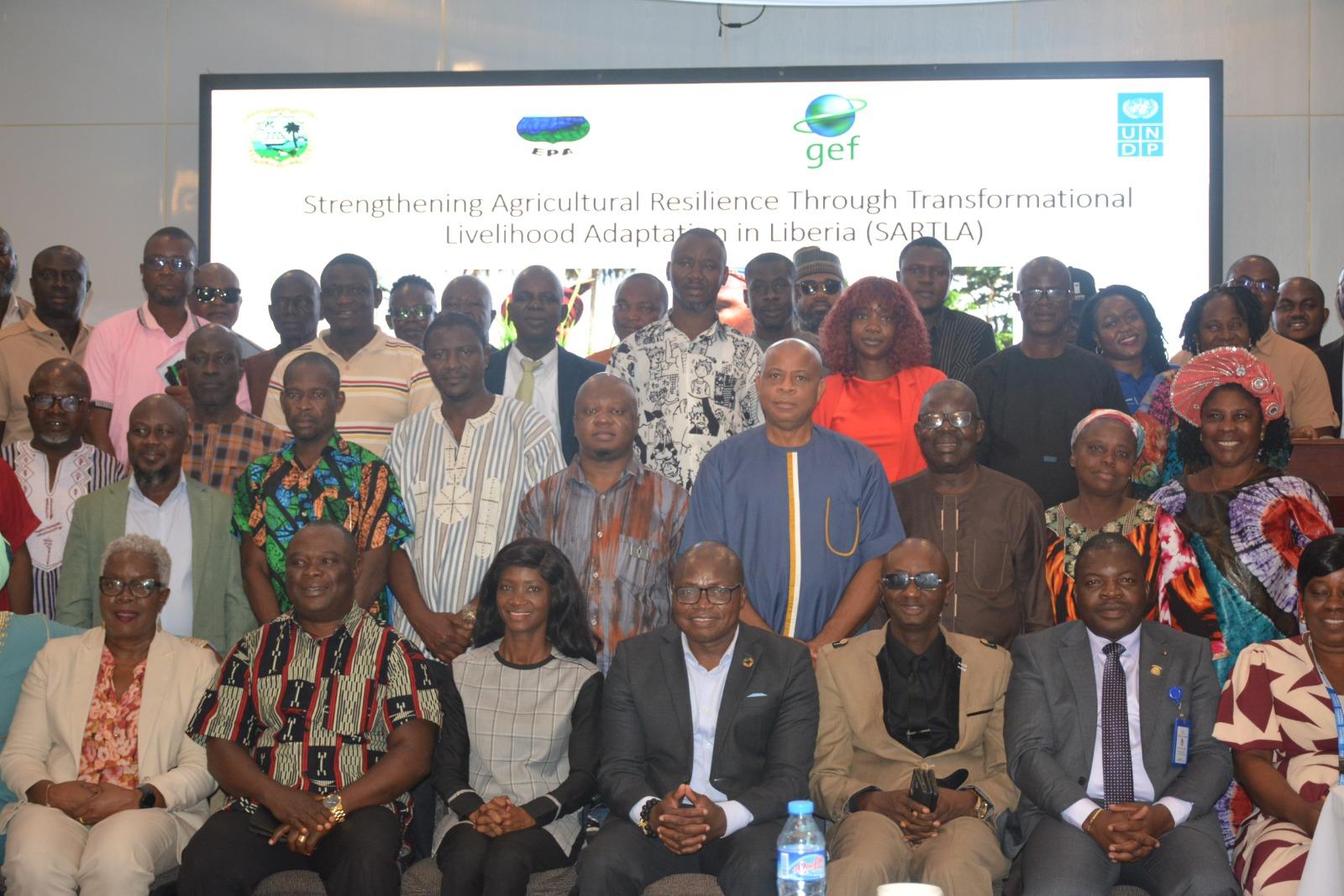 Large group of diverse attendees posing for a group photo at a conference, banner behind.