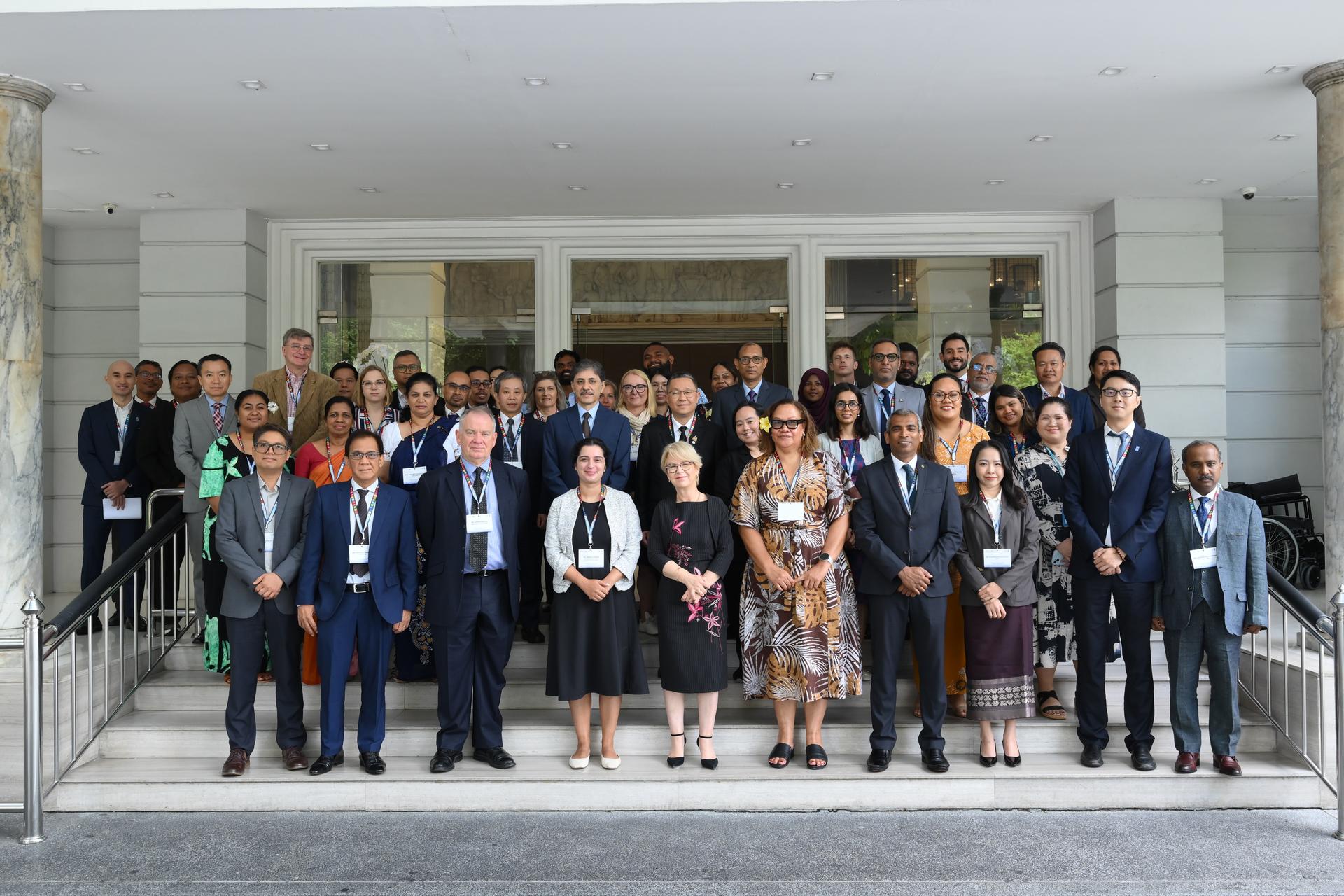 Group photo of professionally dressed people posing on concrete steps outside a modern building.