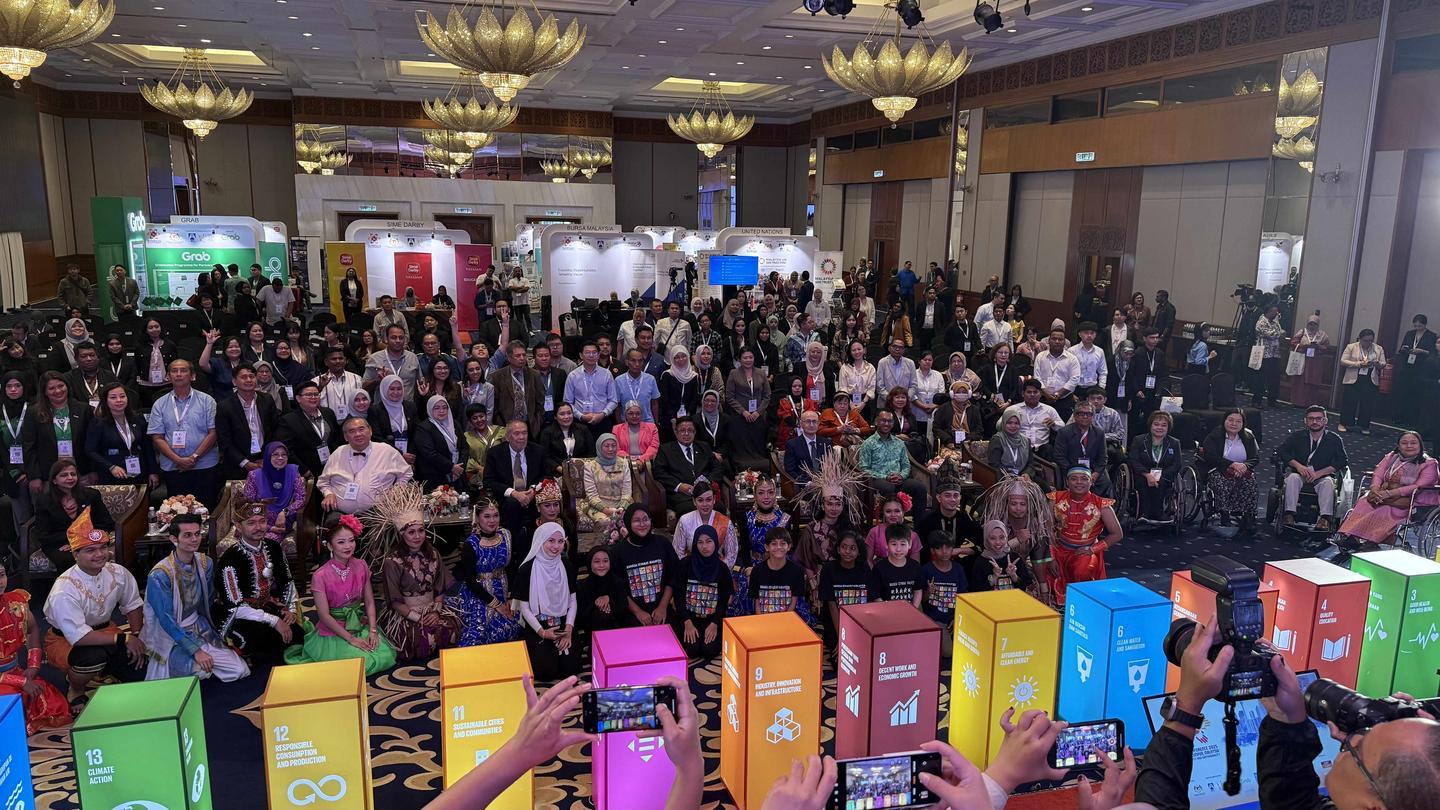 Photograph of a large crowd gathered in a banquet hall, with colorful boxes in the foreground.
