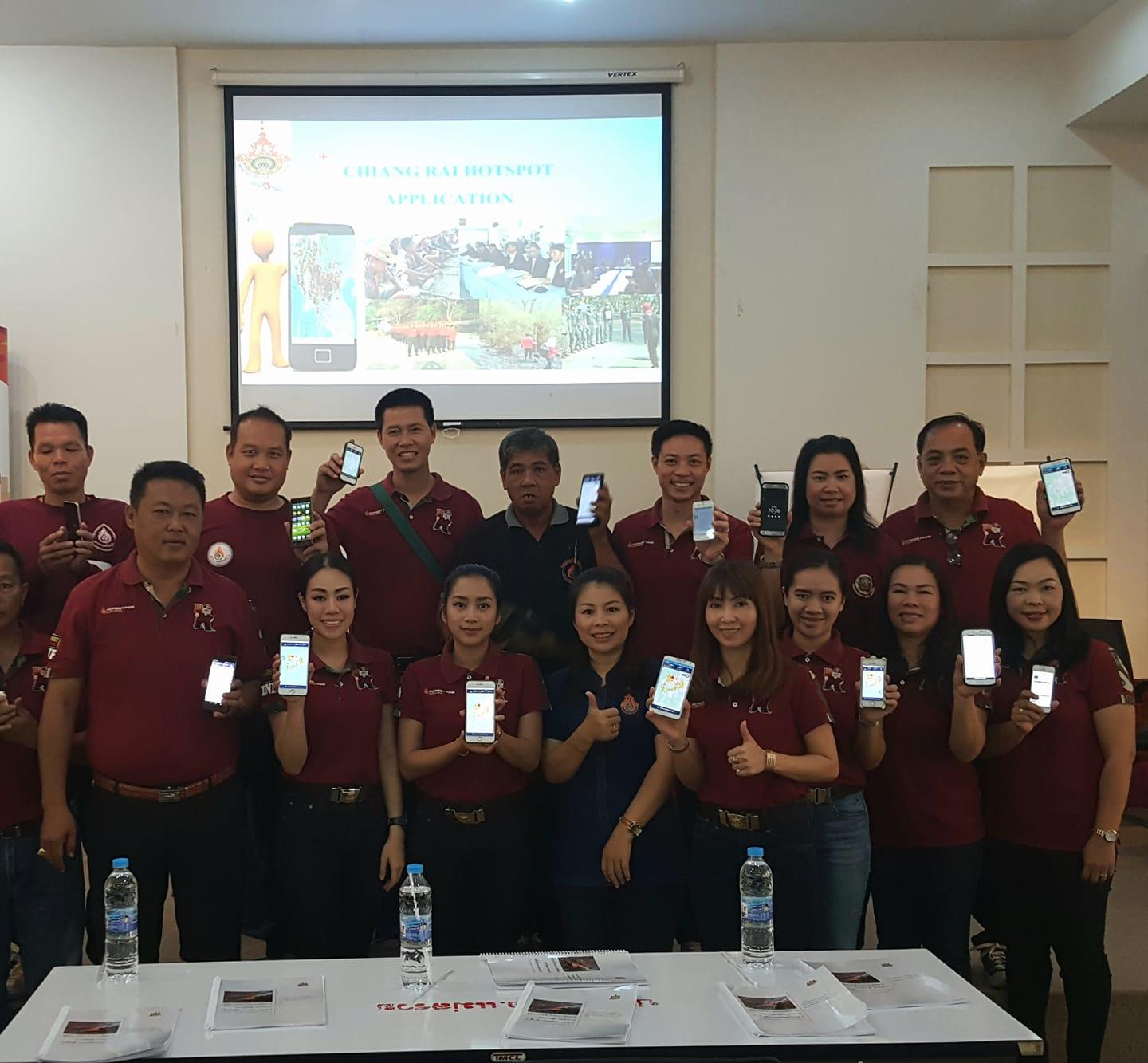 Group photo of participants in maroon shirts posing in a classroom with a projector screen.