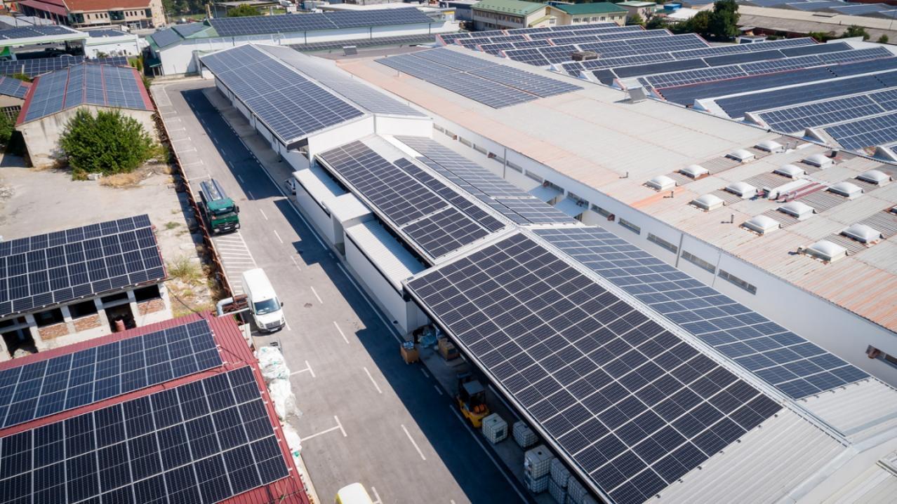 Aerial view of solar panels on flat rooftops across a building complex.