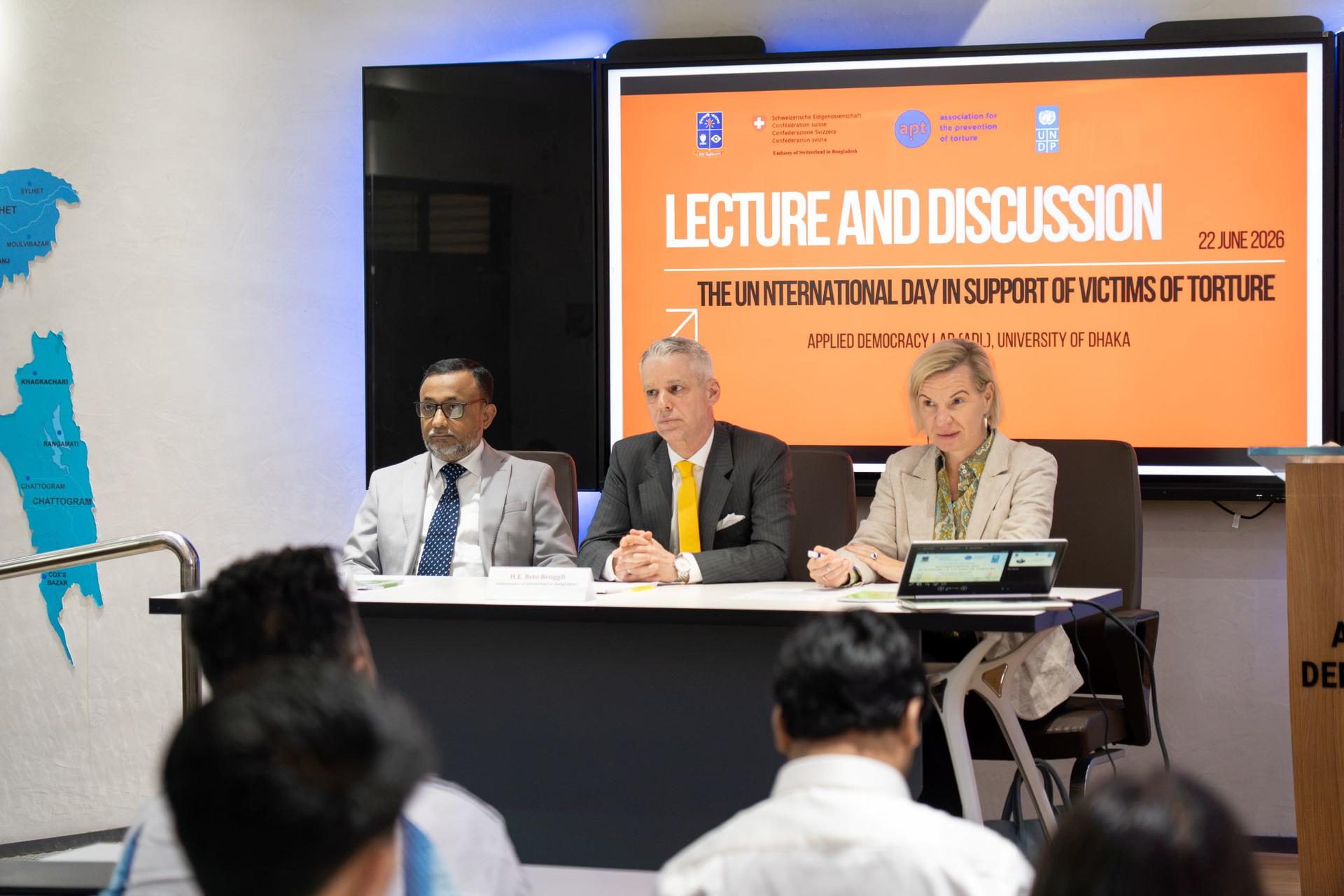 Photograph of a three-person panel at a lecture and discussion event, audience in the foreground.