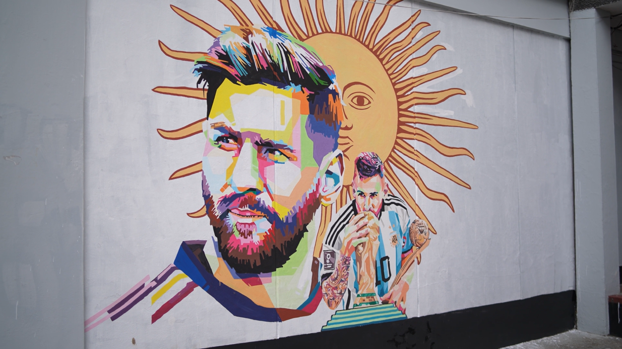 Colorful mural of a bearded man with bright hair and a sunburst behind him.