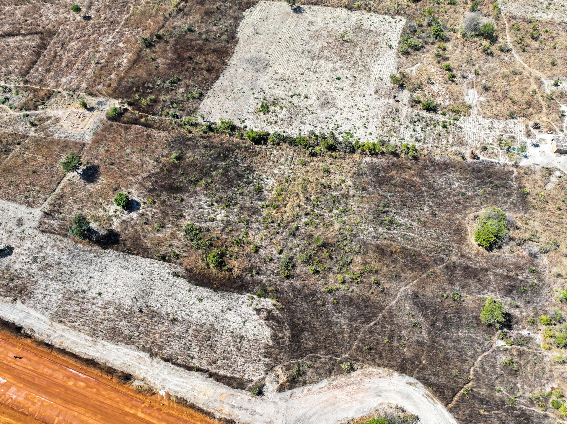 Aerial photograph of the hub site, currently consisting of arid brown fields with sparse shrubs and a curved light-colored road.