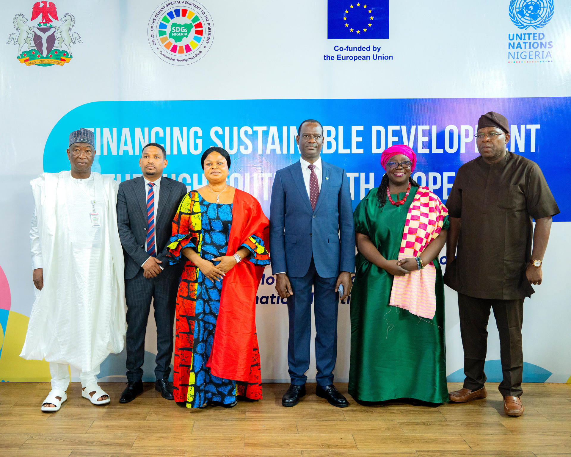 Diverse officials in formal and traditional dress pose at Sustainable Development conference.