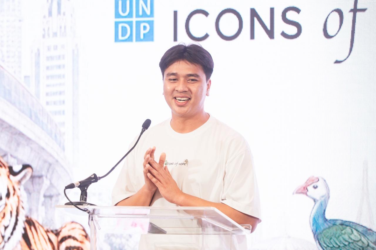Photograph of a man at a podium with UNDP branding; a tiger and peacock visible.