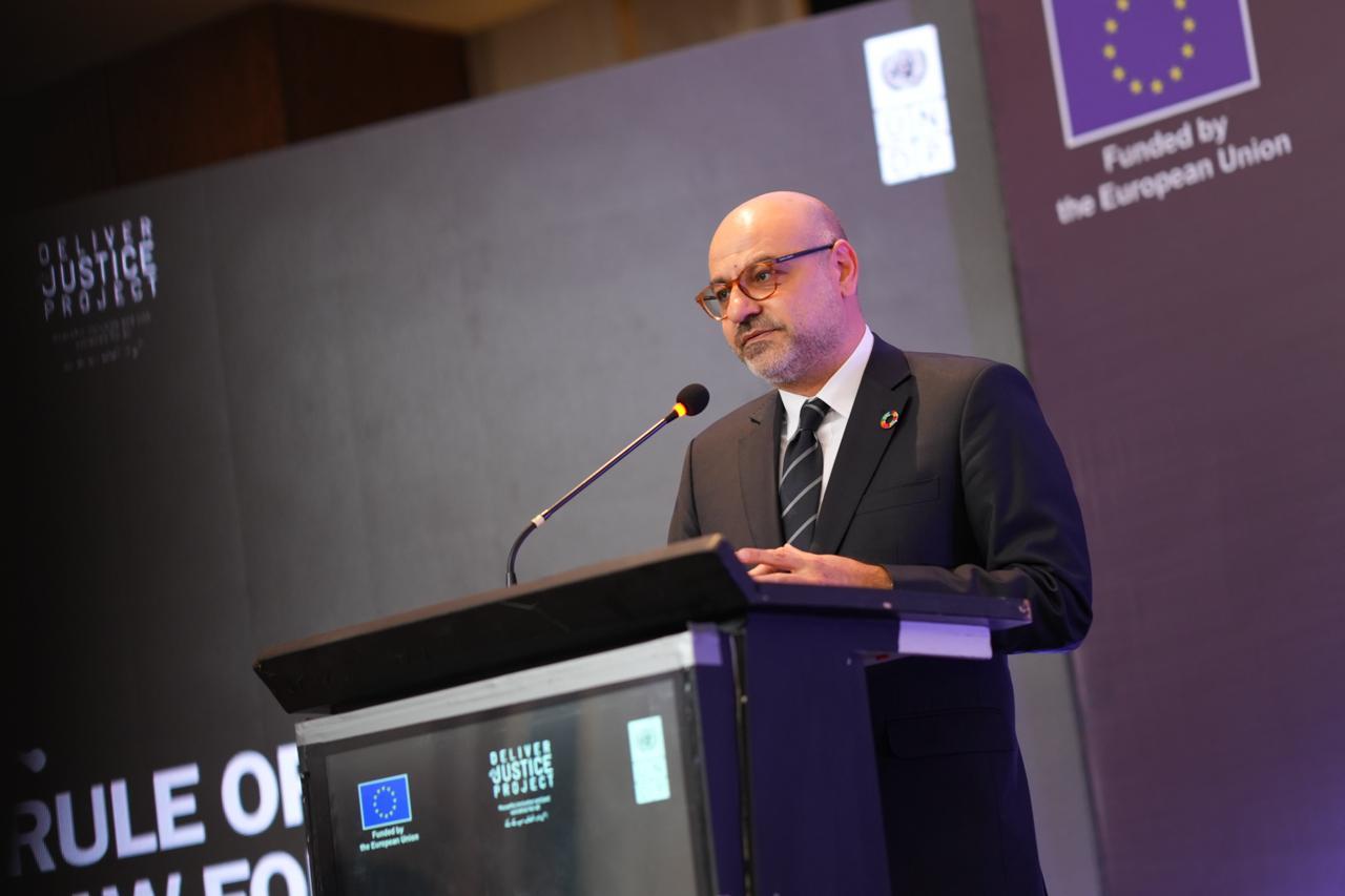 Photograph of a man in a suit speaking at a podium on a conference stage with EU banners.