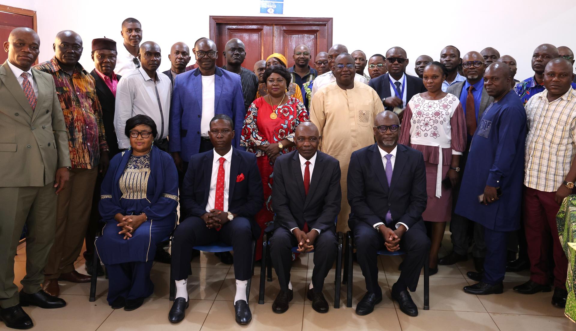 Group photo of men and women in formal attire posing indoors.