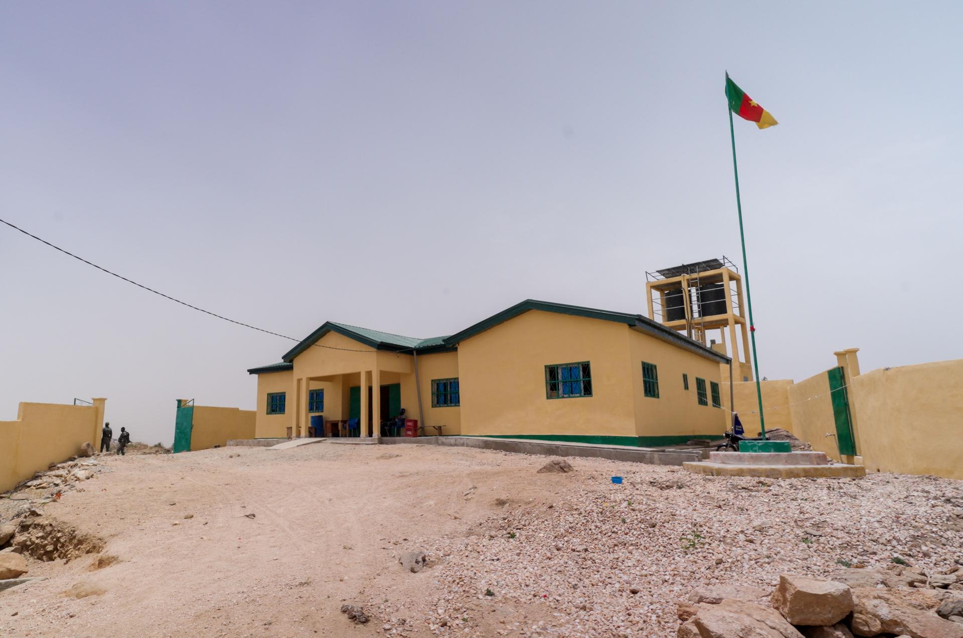 Desert one-story yellow building with small bell tower and flagpole in front.