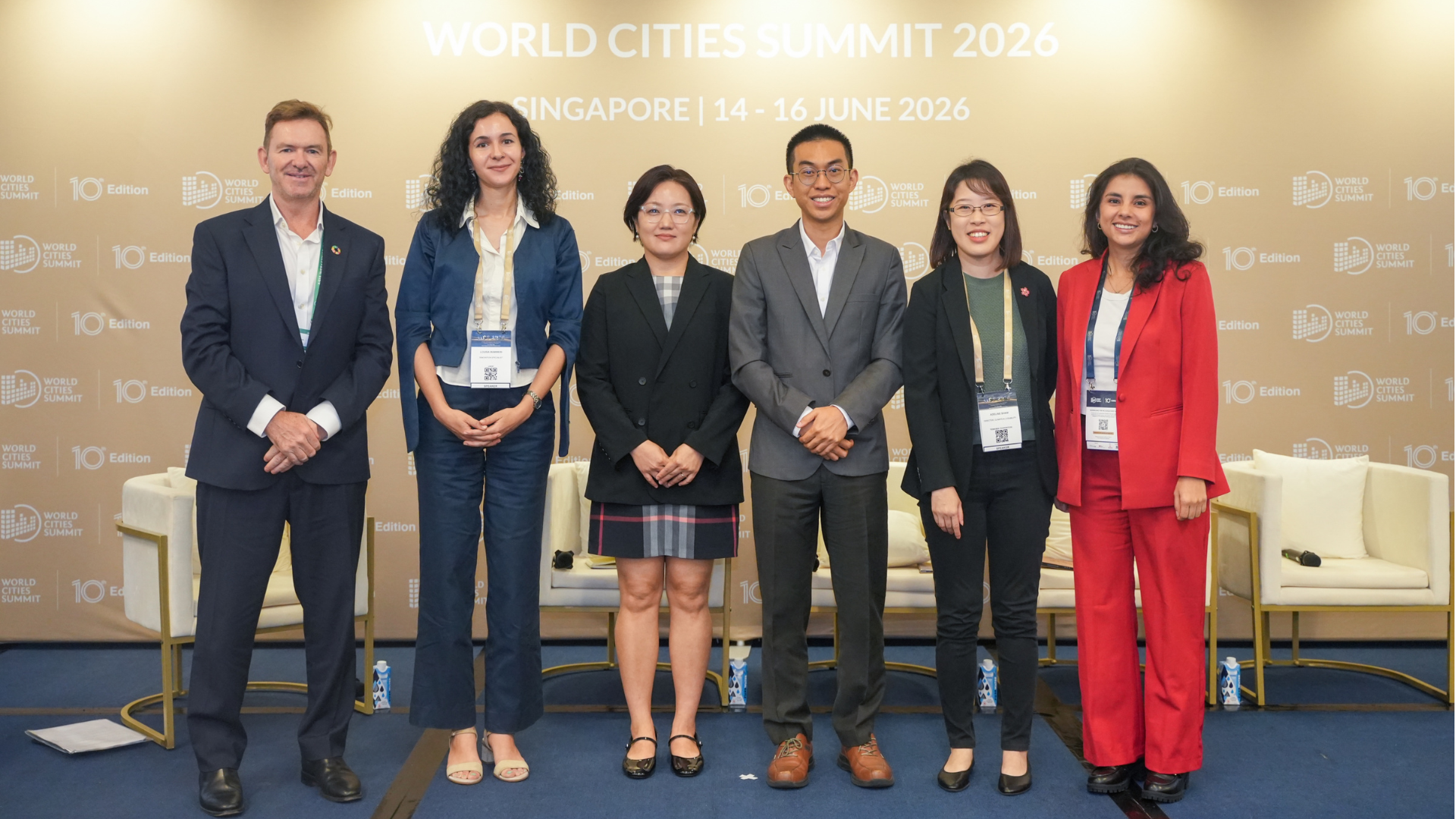 Group photo of six speakers on a stage at the World Cities Summit 2026, Singapore.