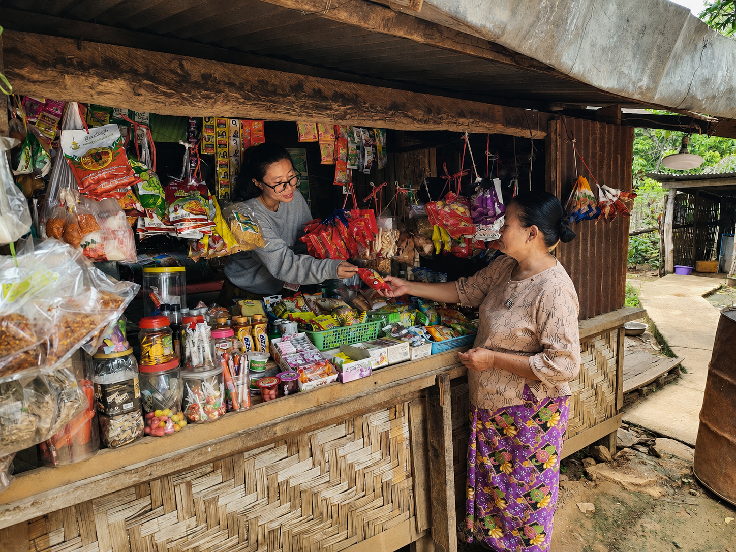 Outdoor market stall with a vendor helping a customer; shelves lined with jars and snacks.