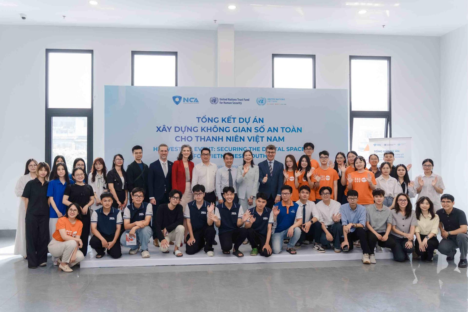 Large group posing for a photo in a conference room with a banner behind them.