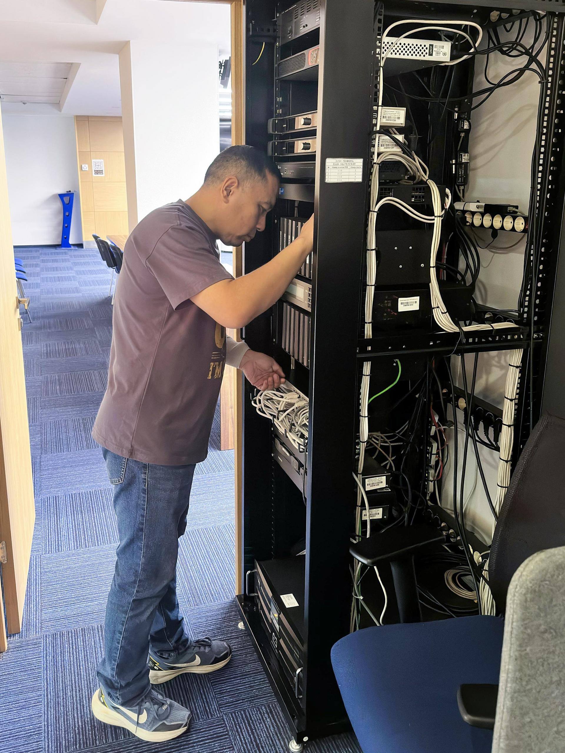 Technician adjusts cables inside an open server rack in a data center.