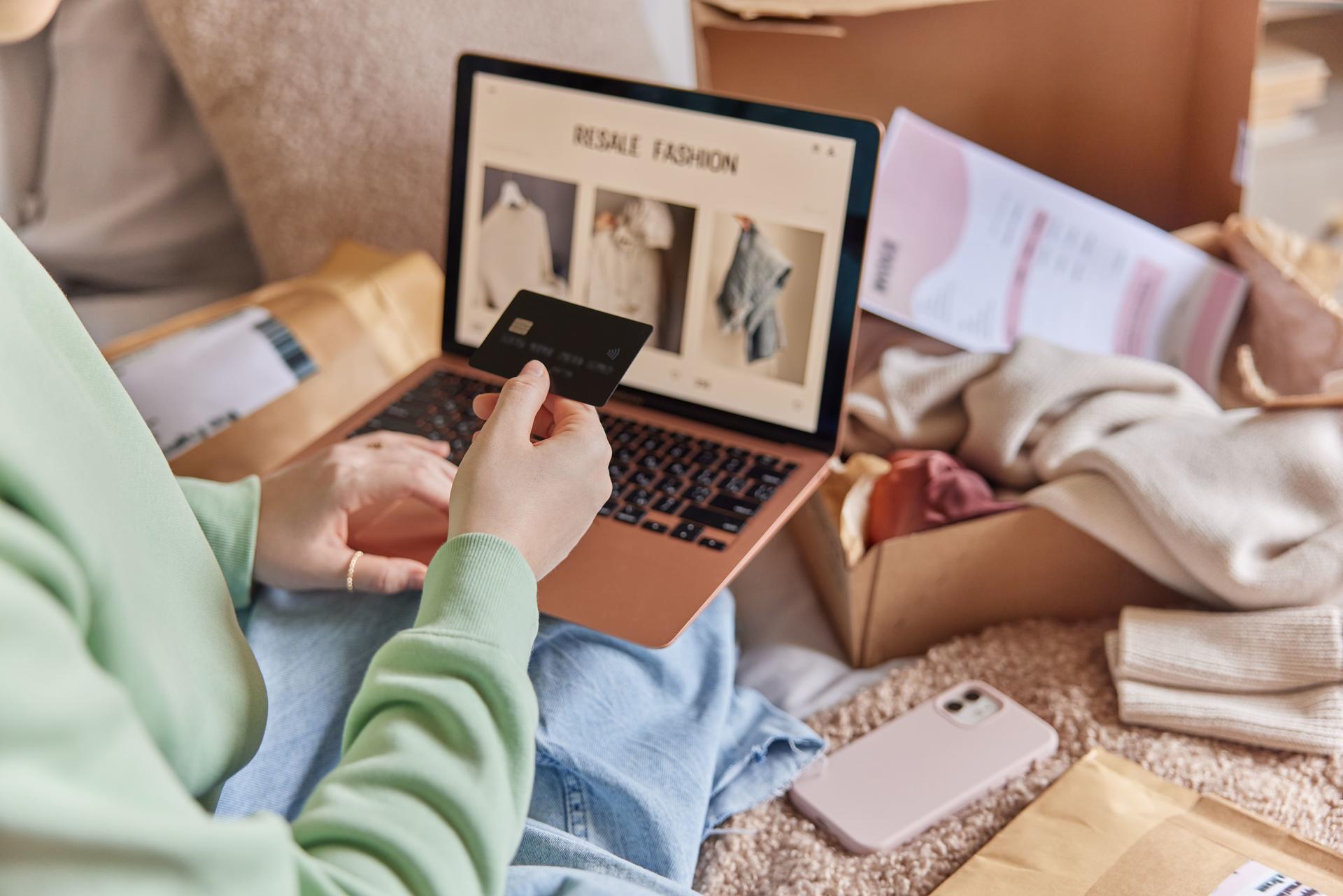 Two people on a bed, looking at a laptop displaying fashion lookbook, with photos scattered around.