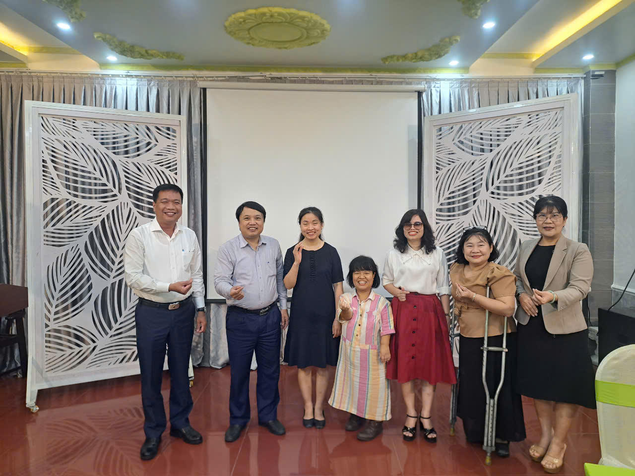 Group of eight people posing in a decorated hall with white lattice screens.
