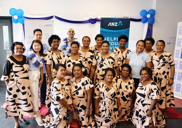 Group of people in matching leopard-print outfits posing for a photo at a blue-themed event.