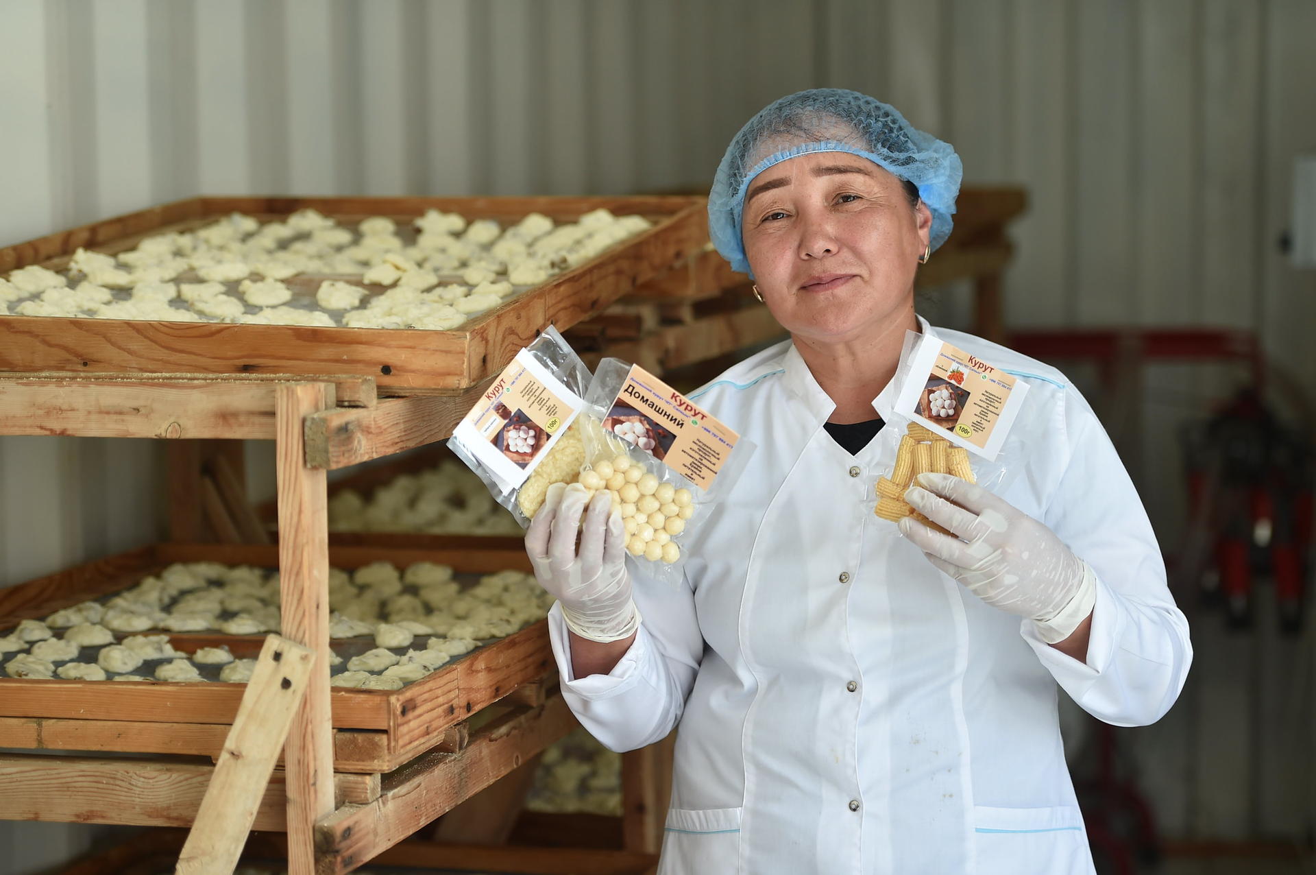Photograph of a bakery worker in a white coat and hairnet, holding two chocolate bars.