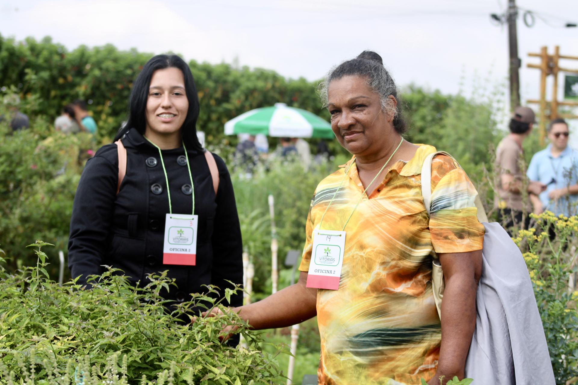 Photo of two people posing in a garden, wearing name badges at an outdoor event.