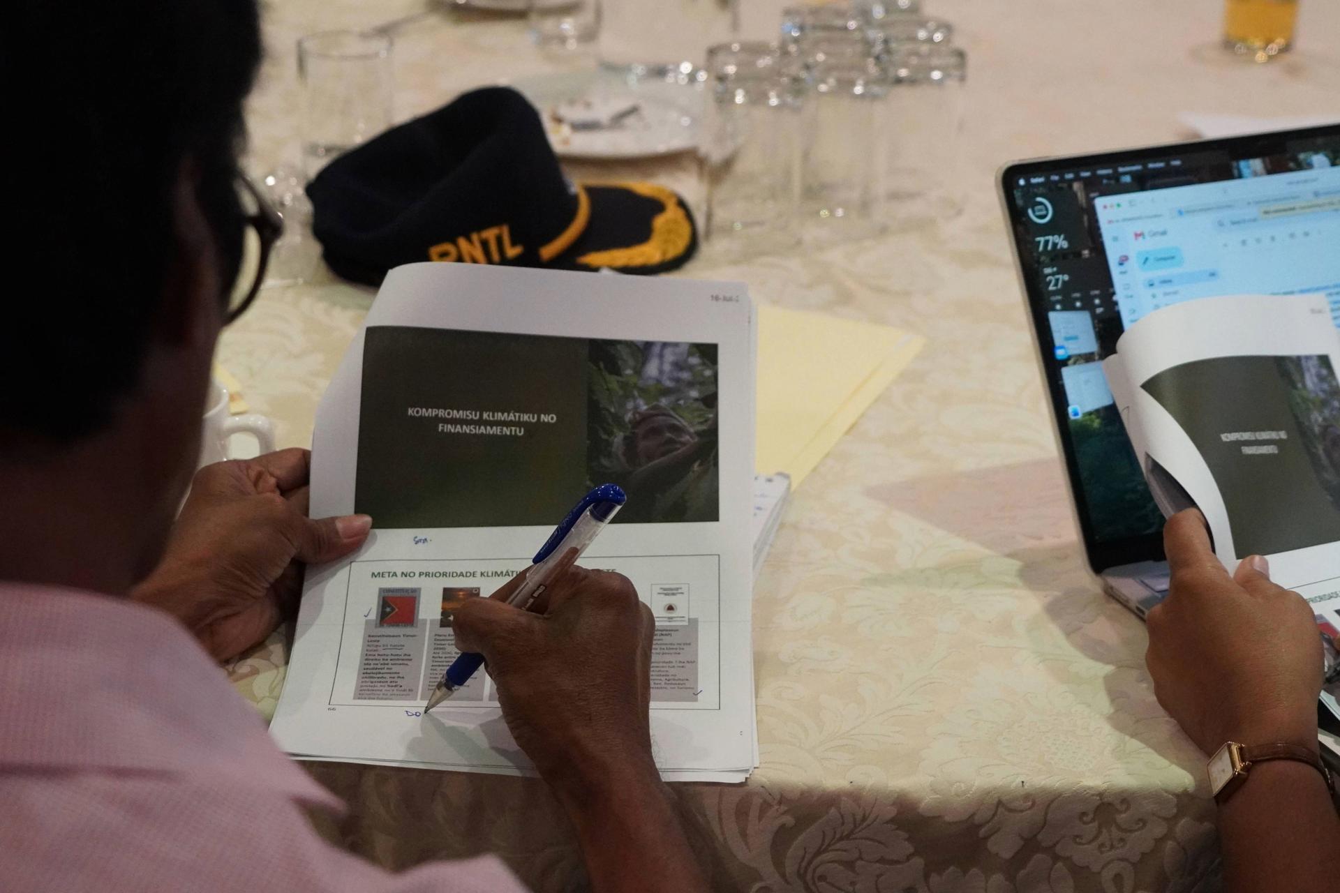 Two people at a table using tablets; one writes with a stylus.