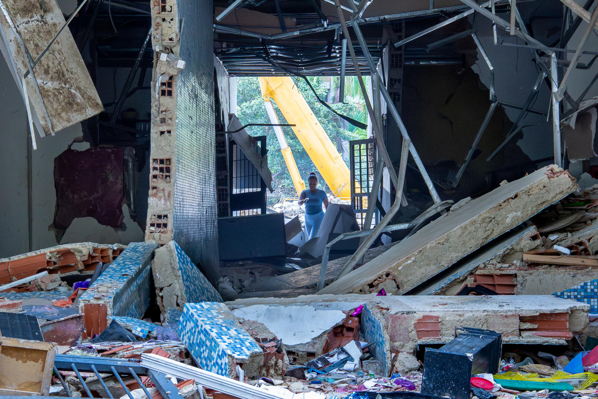 Interior of a collapsed building with rubble, exposed beams, and scattered debris.