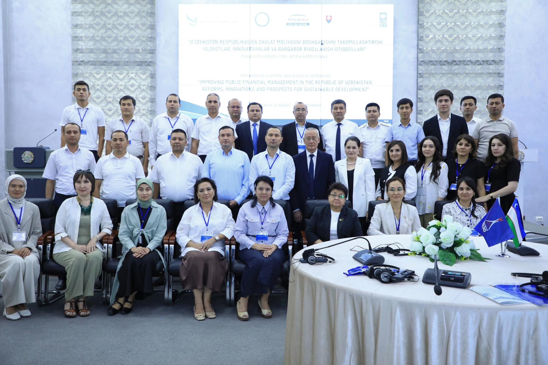 Photo: large group of professionals posing for a conference group photo in a banquet hall.