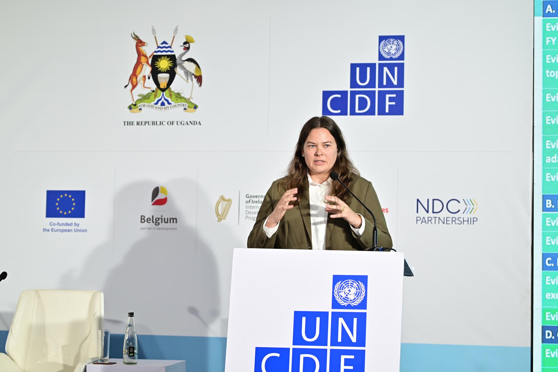 Photograph of a woman speaking at a UN conference podium with UN CDF banners and an EU flag.